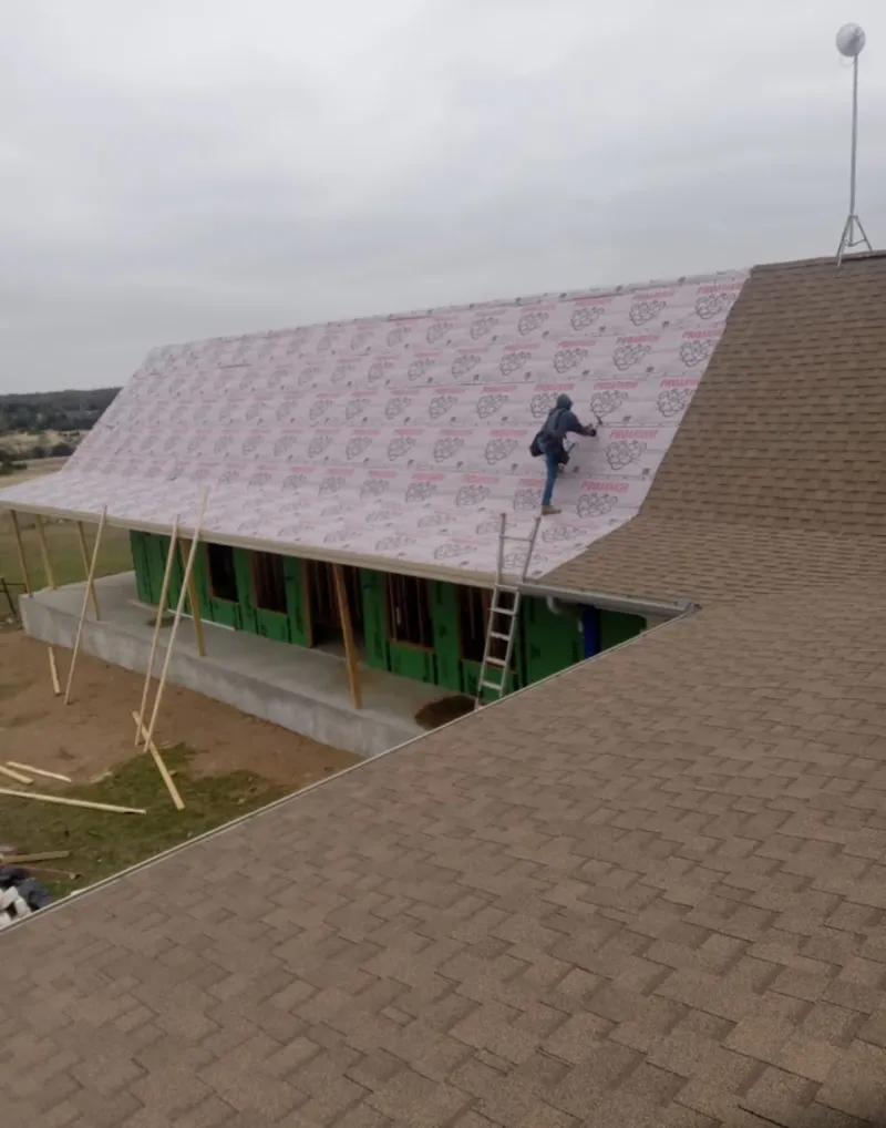 Worker preparing underlayment for a metal roof installation in Crown Point